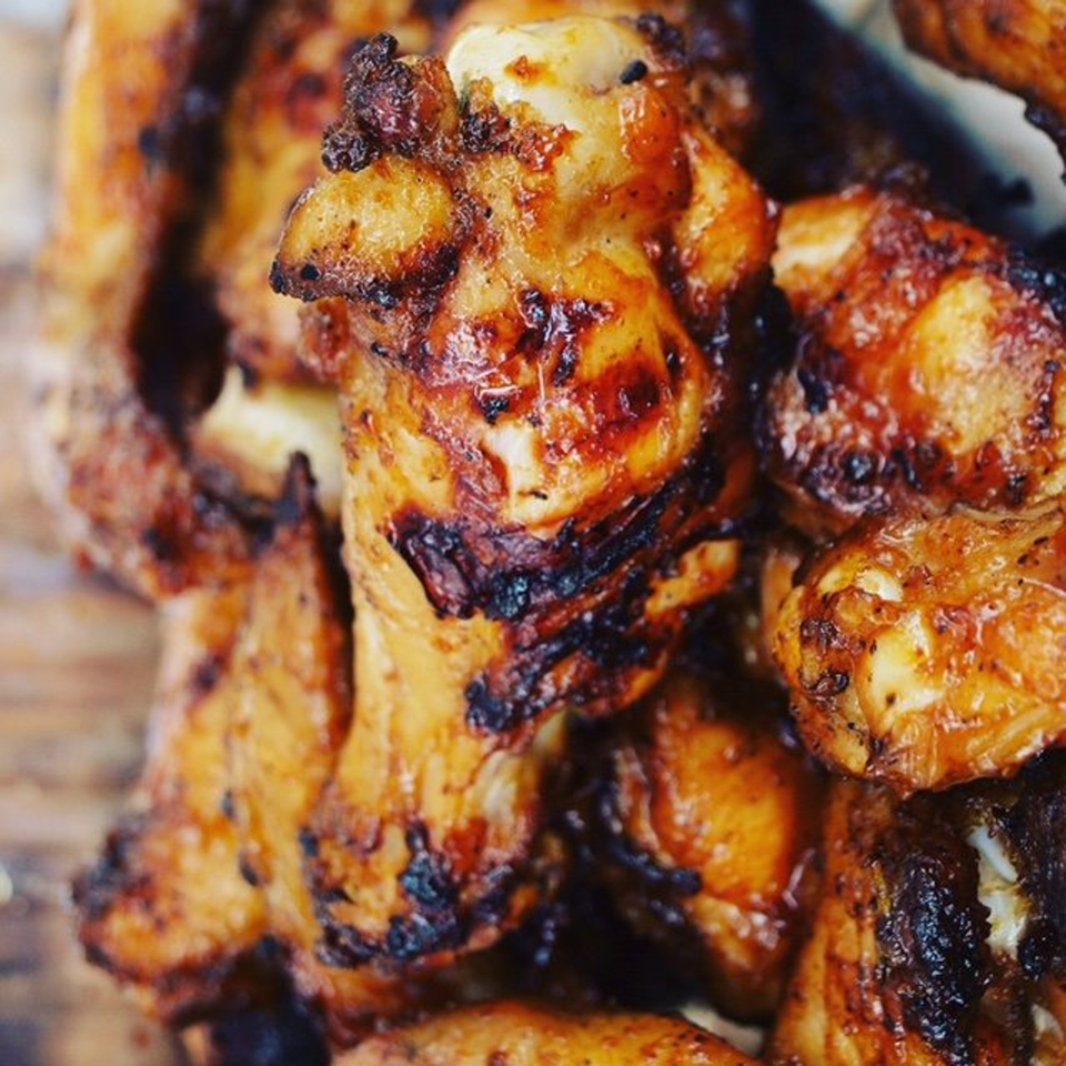 Close-up of golden-brown grilled chicken wings with charred edges, ready to be served.
